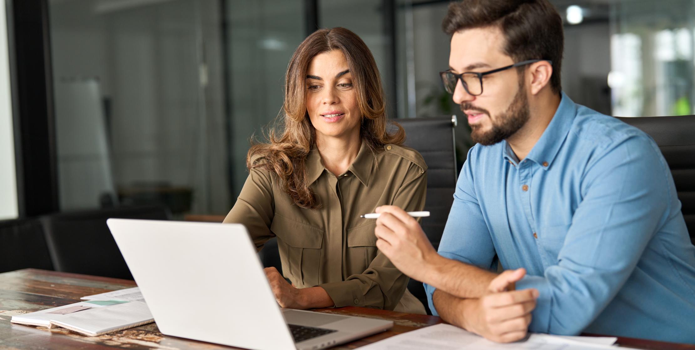 Zwei Personen arbeiten gemeinsam und schauen auf einem Laptop
