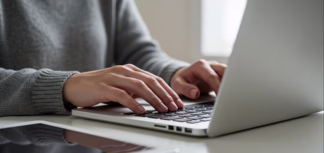 Bildausschnitt einer Person, die etwas auf dem Laptop eintippt