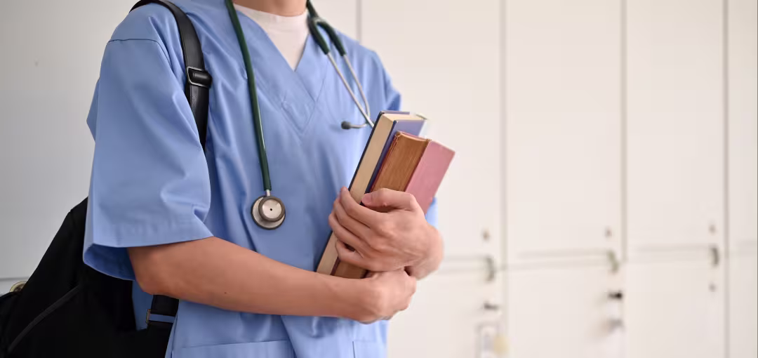 Person trägt Arztkittel und hält Bücher in der Hand